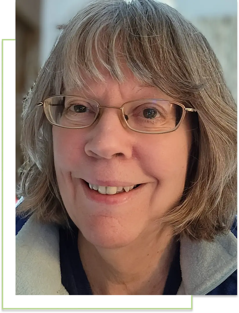 Smiling woman with glasses and gray hair.